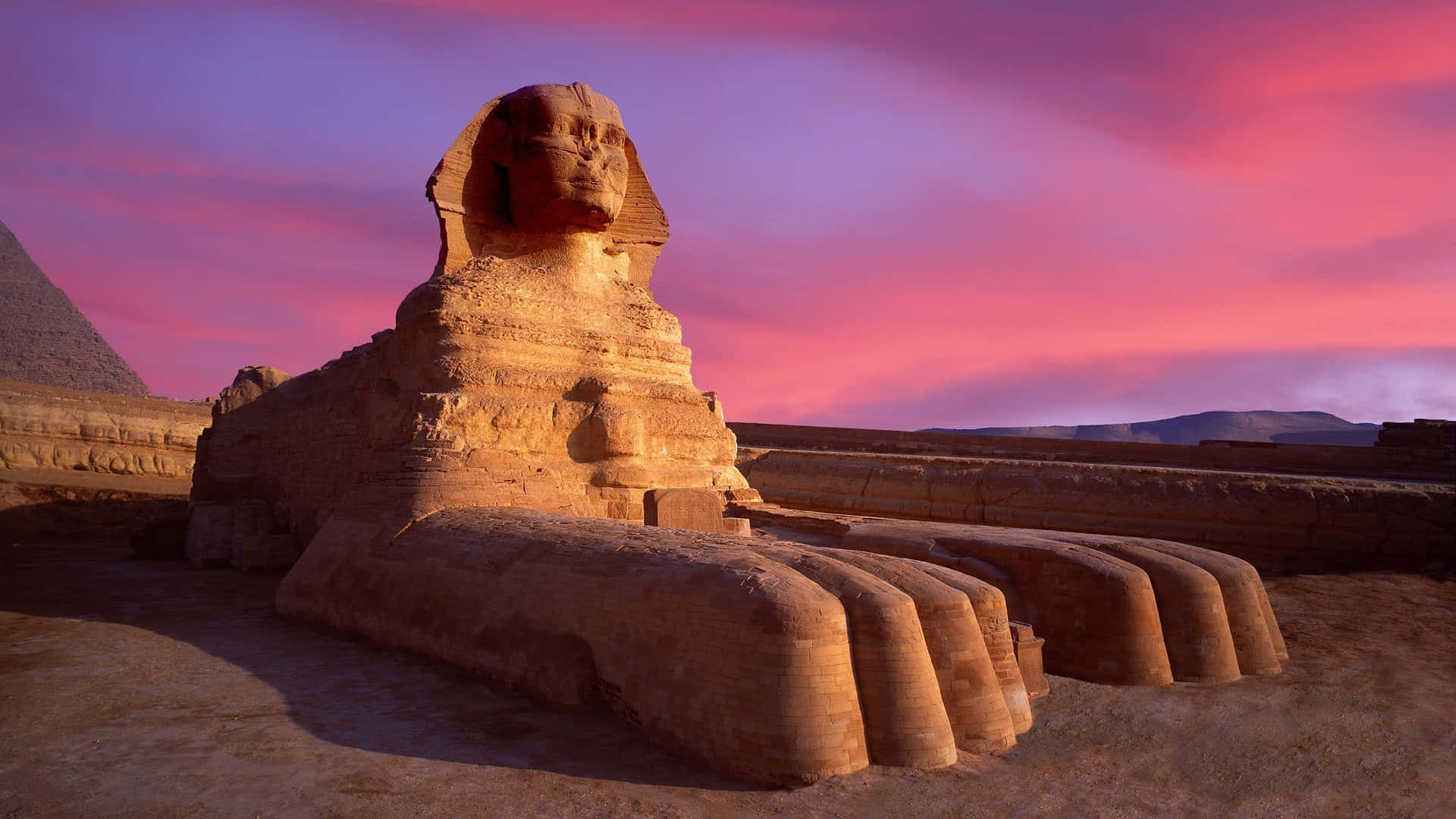 En sphinx og pyramider ved solnedgang Wallpaper