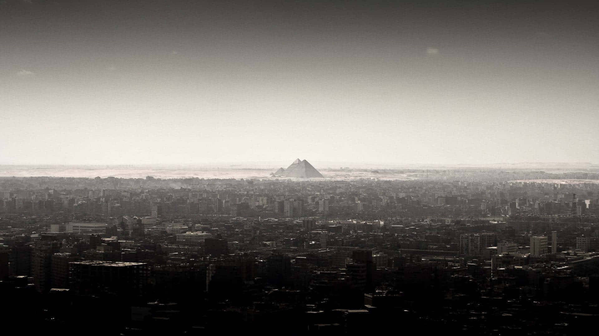 Et sort og hvidt foto af en by med et bjerg i baggrunden. Wallpaper