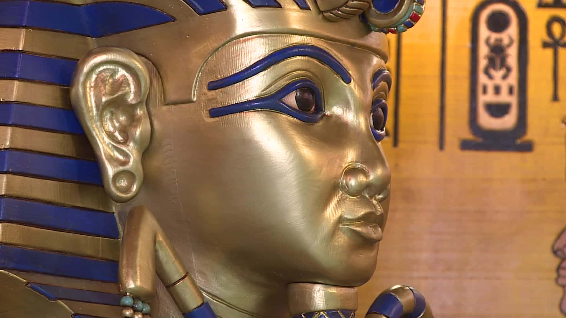 A Statue Of An Egyptian Pharaoh With Gold And Blue Eyes Wallpaper