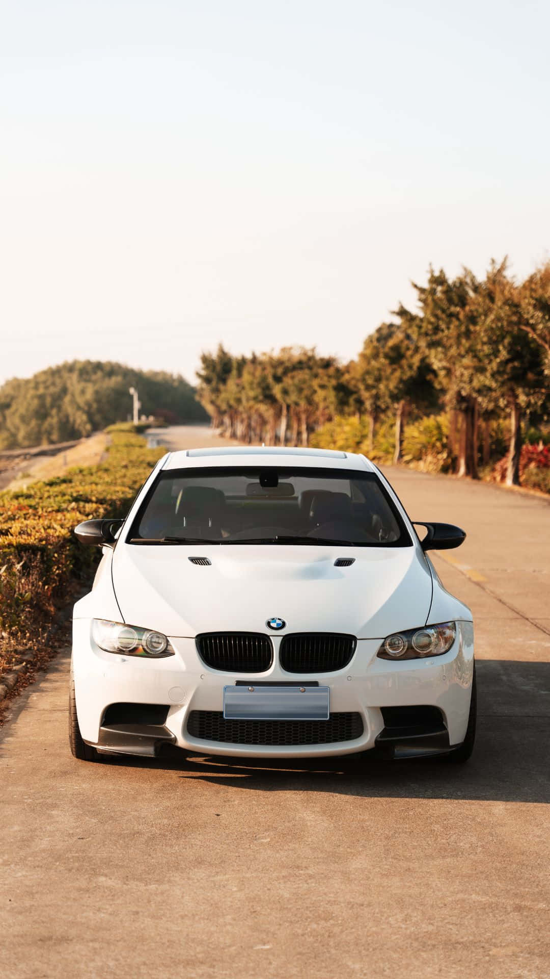 En hvid BMW M3 parkeret på en vej