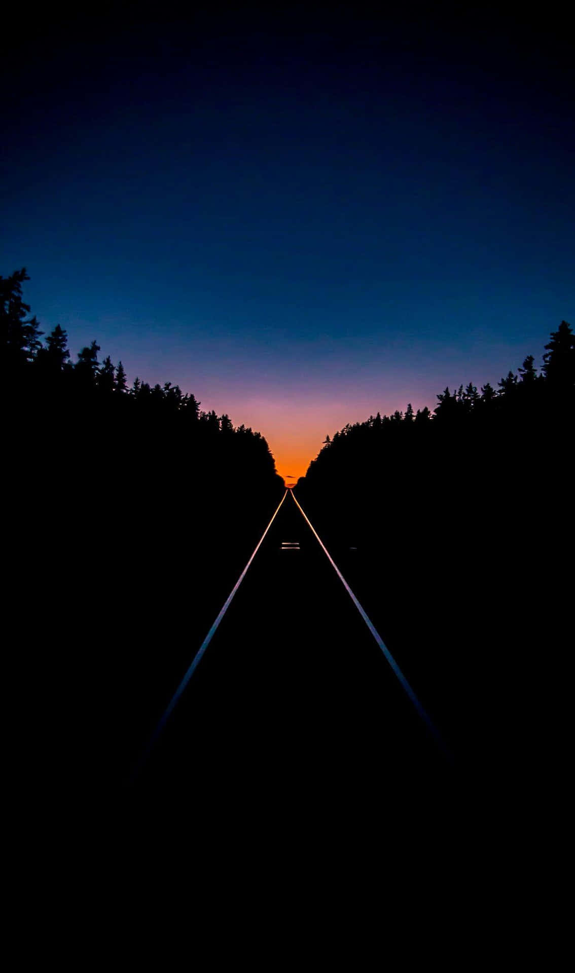A Train Track With A Sunset Behind It