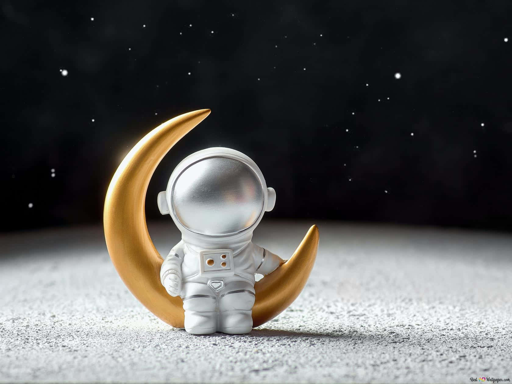En guld astronautfigur siddende på månen Wallpaper