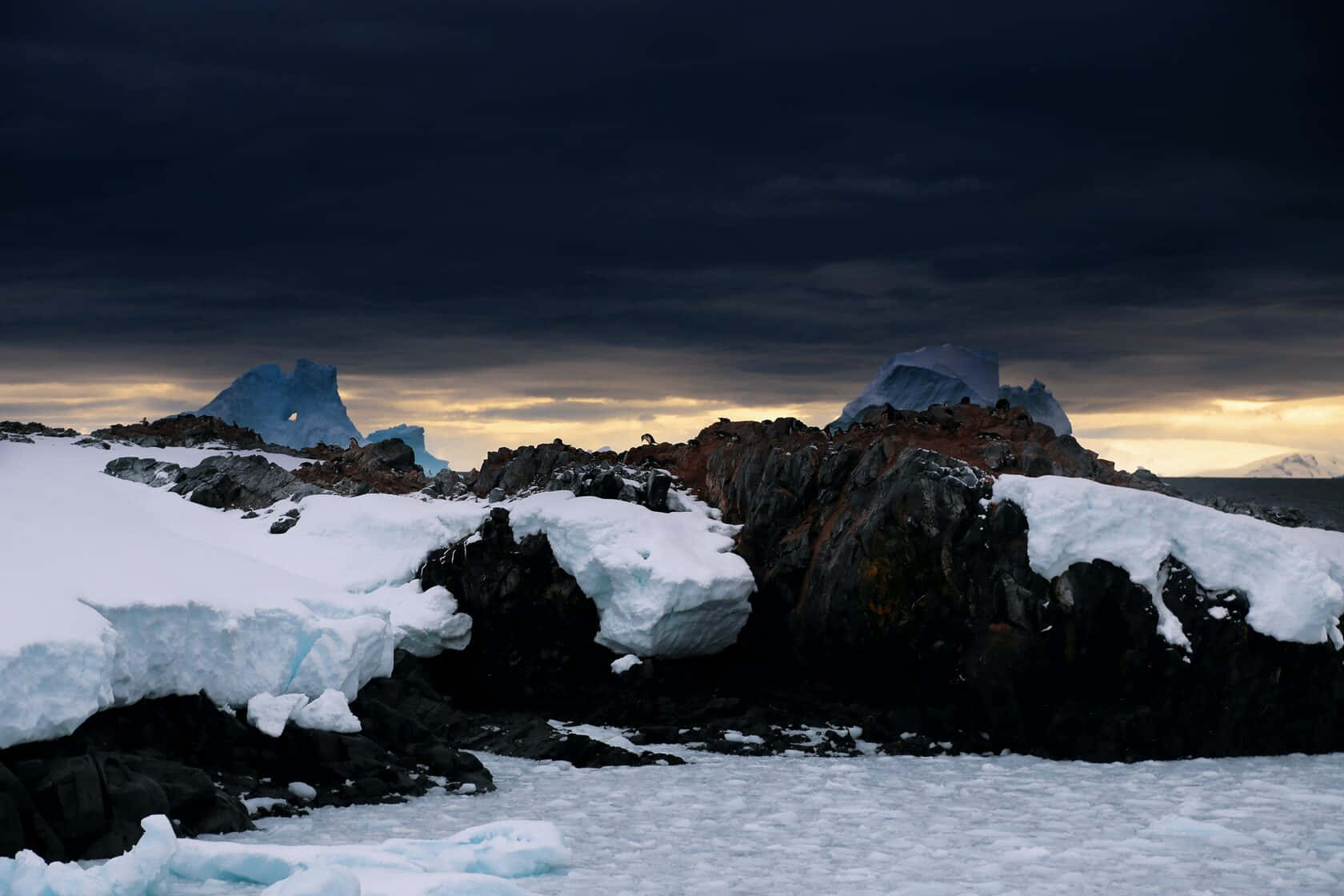 A Dark Sky Over A Rocky Shore With Ice And Rocks
