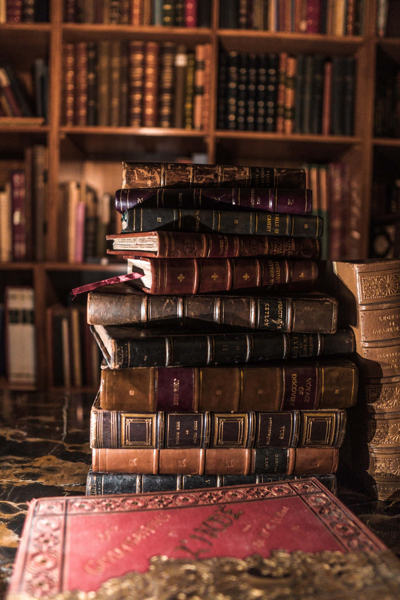 Antique_ Books_ Stacked_ In_ Library Wallpaper