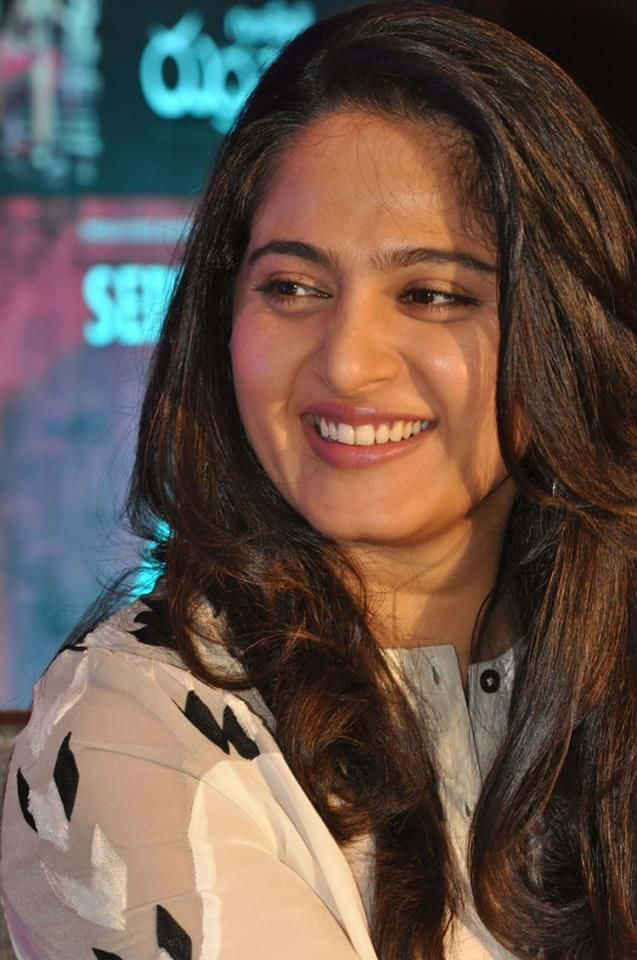 Anushka Shetty Glimlachend Op Evenement Achtergrond