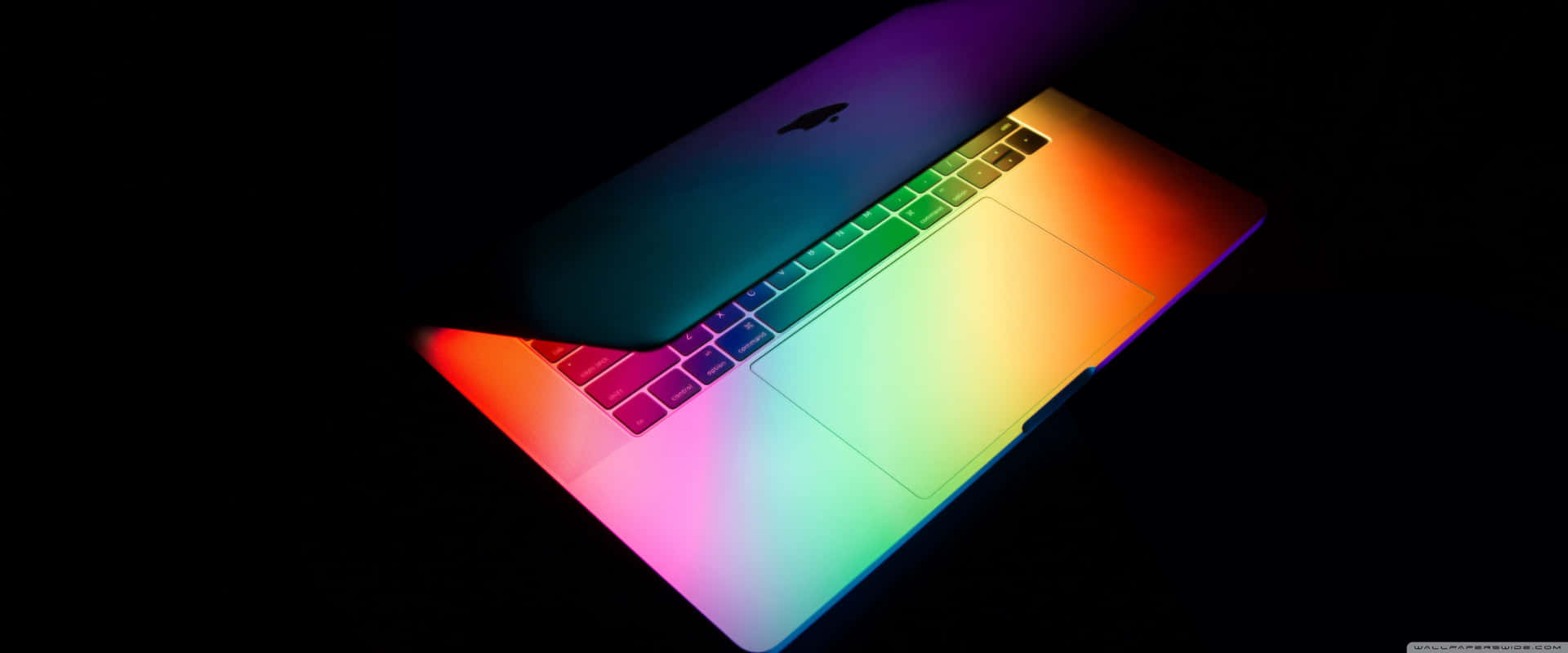 Semuestra Un Macbook Pro De Colores Arcoíris En La Oscuridad. Fondo de pantalla