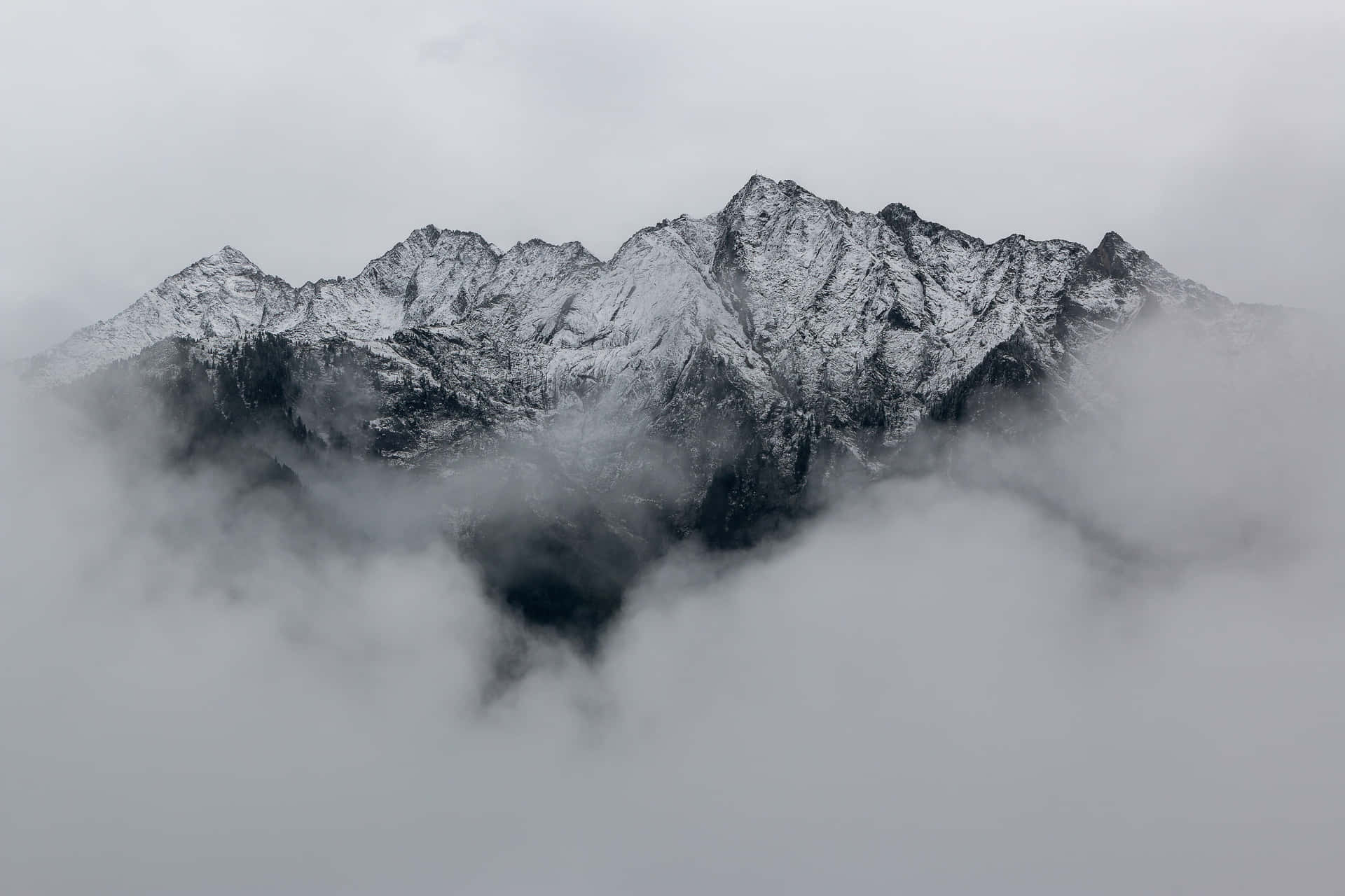 A Mountain Range Covered In Clouds Wallpaper