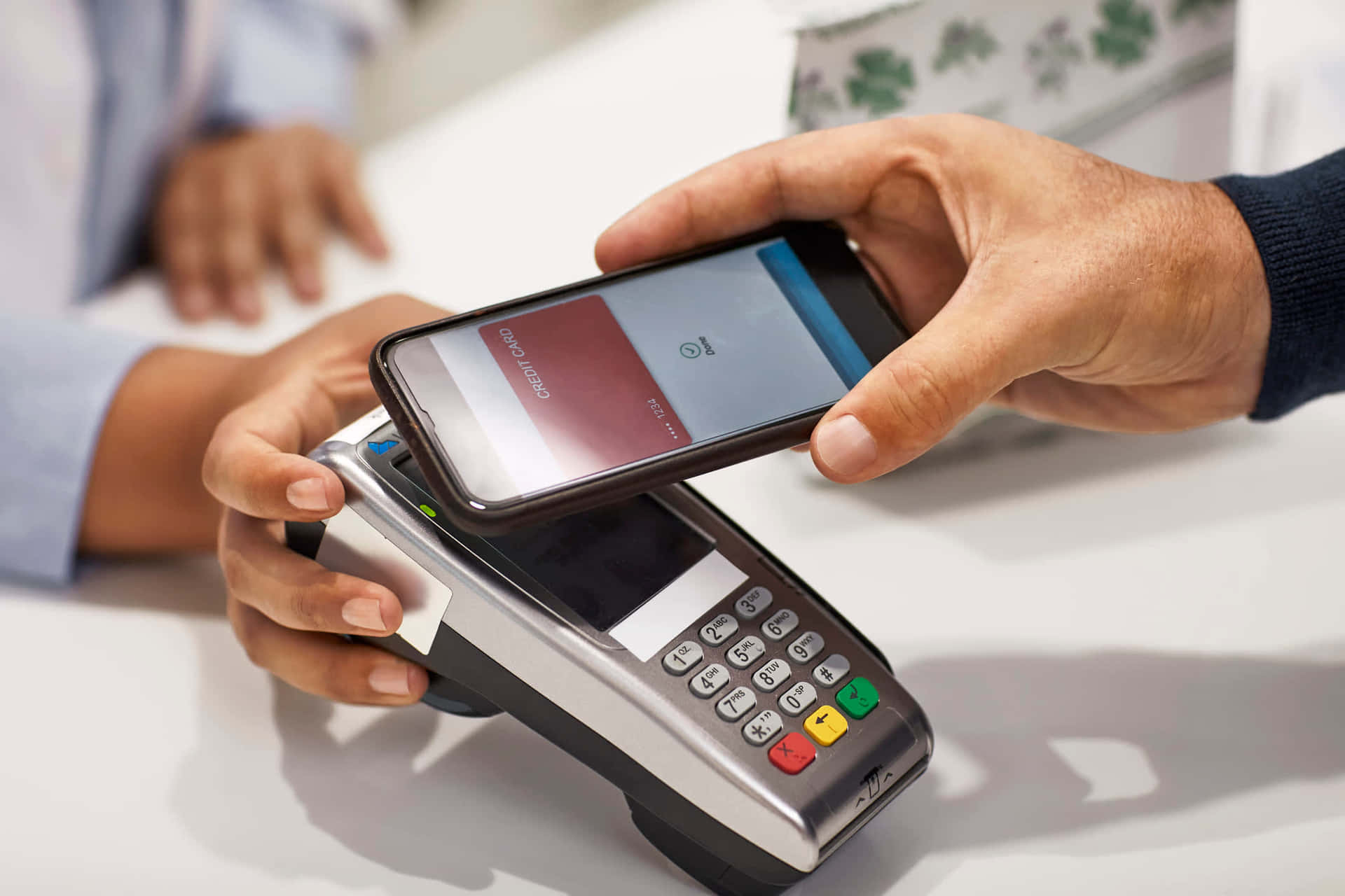 A Person Is Holding A Cell Phone And A Pos Machine