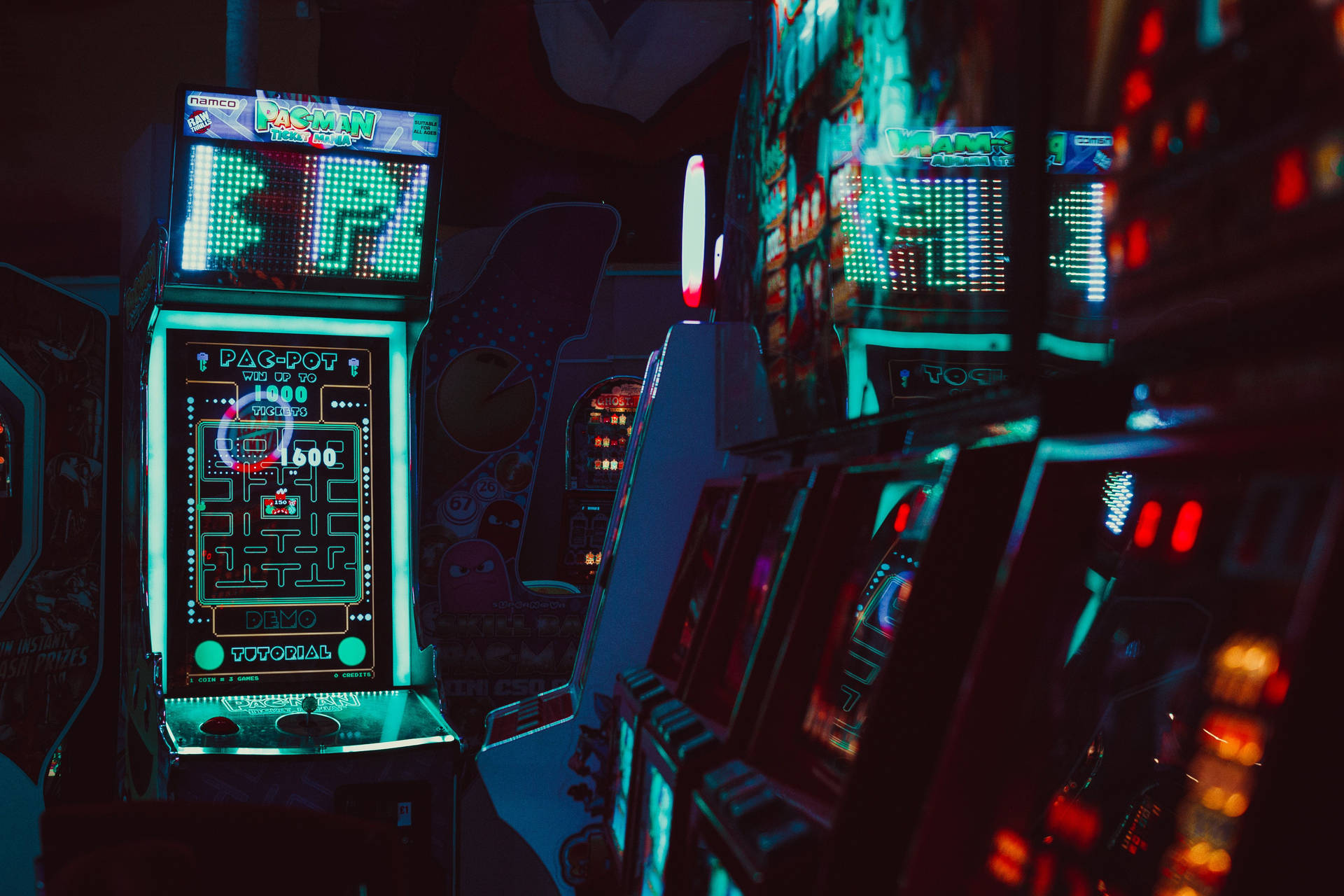 Et mørkt rum med mange gaming maskiner Wallpaper