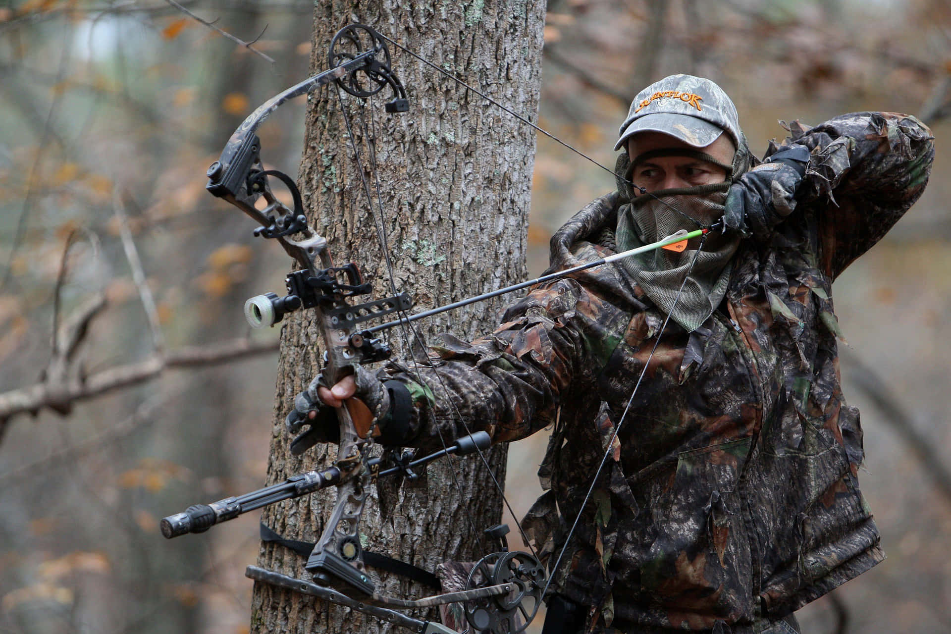 A Man In Camouflage Is Holding A Bow And Arrow