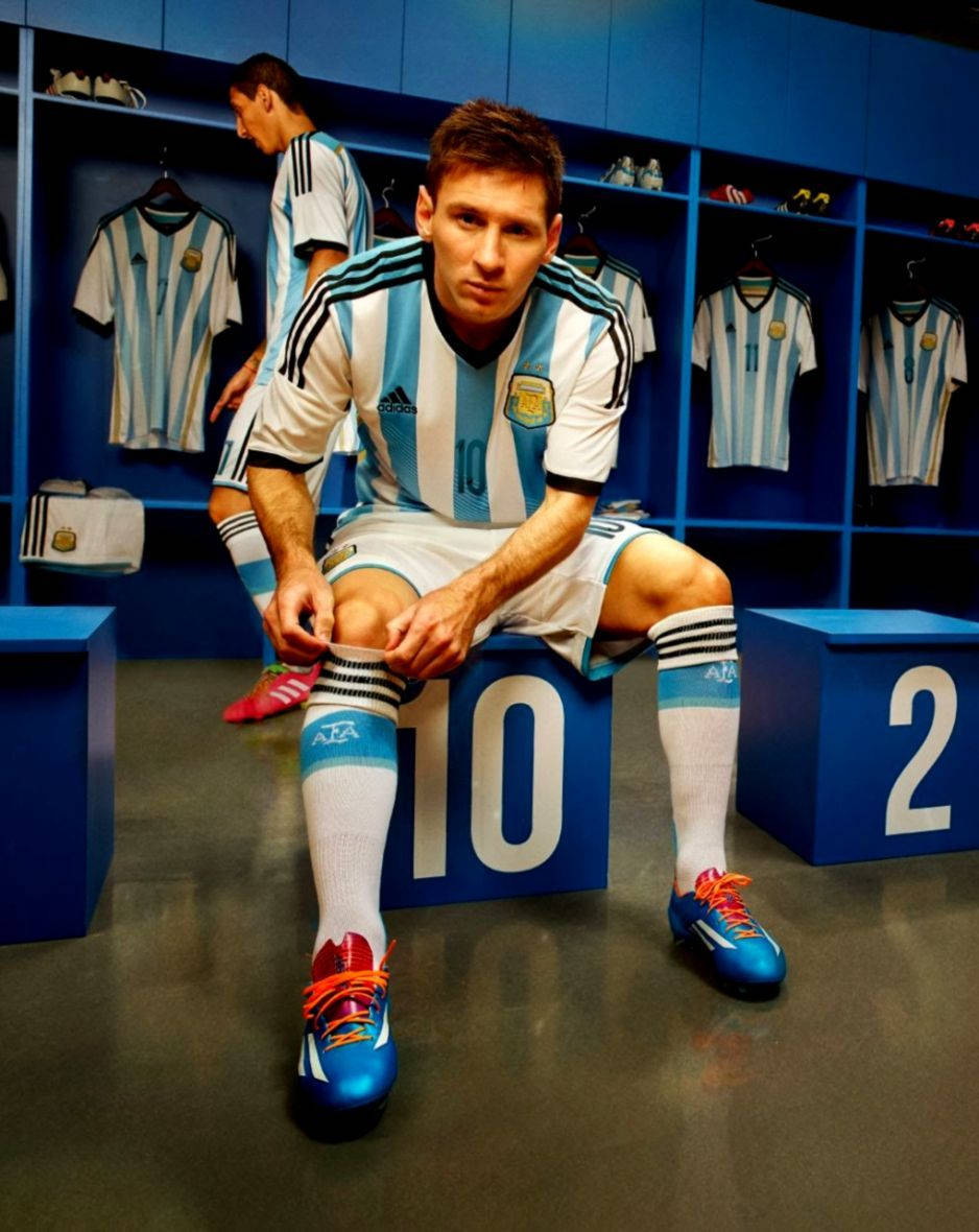 Argentinanational Football Team Messi På Stol. (this Would Make Sense In The Context Of A Computer Or Mobile Wallpaper, As It Is Describing An Image Of Messi On A Chair With The Argentina Team In The Background.) Wallpaper