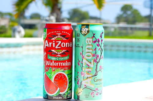 Two Cans Of Watermelon And Watermelon Soda Next To A Pool Wallpaper
