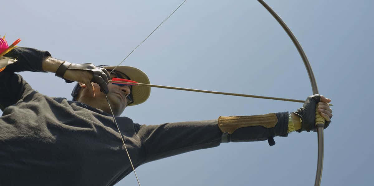 A Man Is Aiming His Bow At A Target