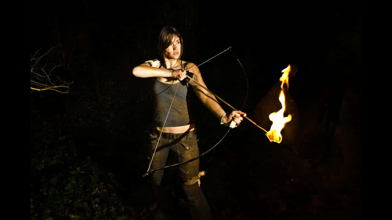 A Woman Holding A Bow And Arrow In The Dark
