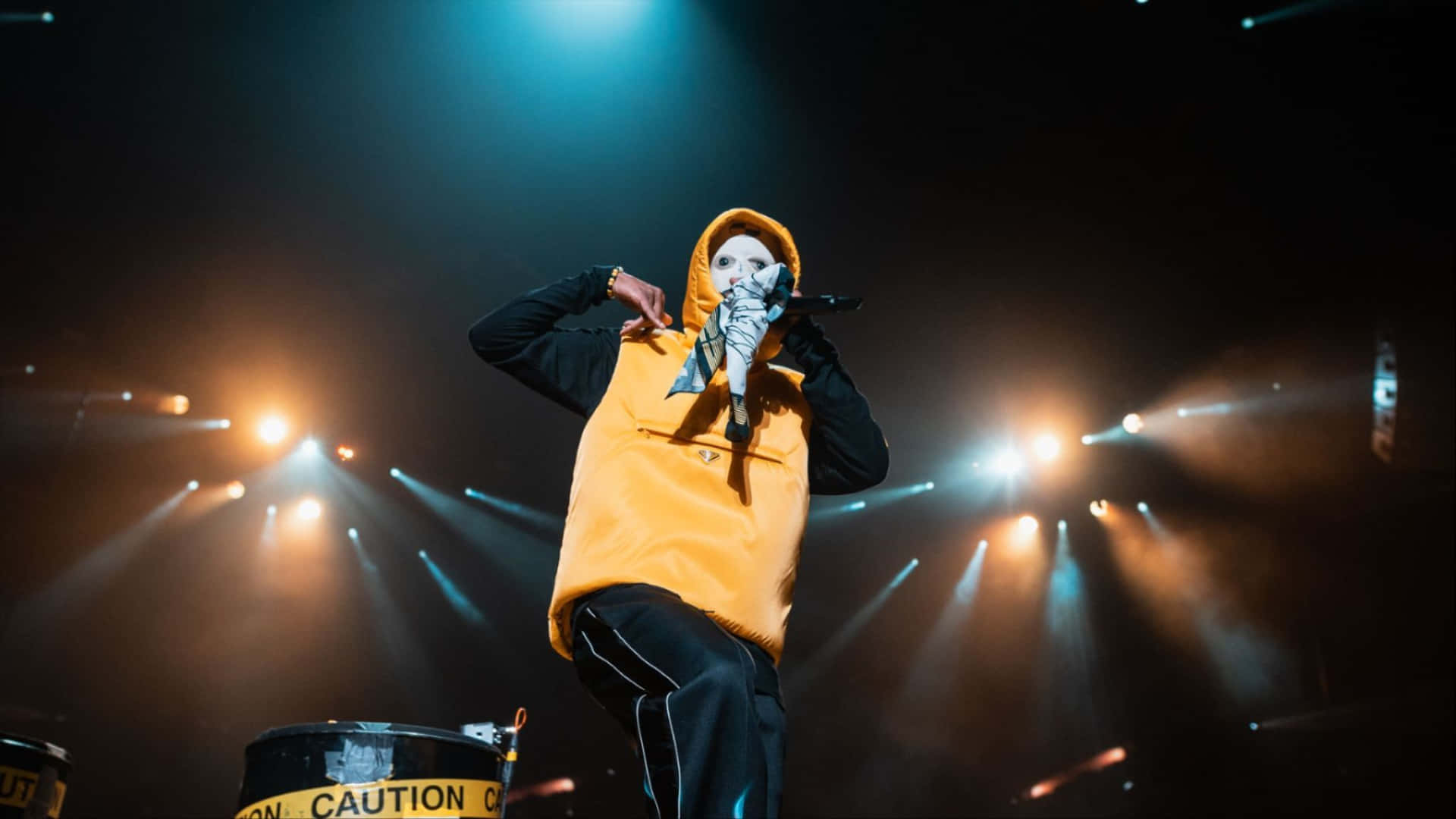 A Man In A Yellow Hoodie On Stage Wallpaper