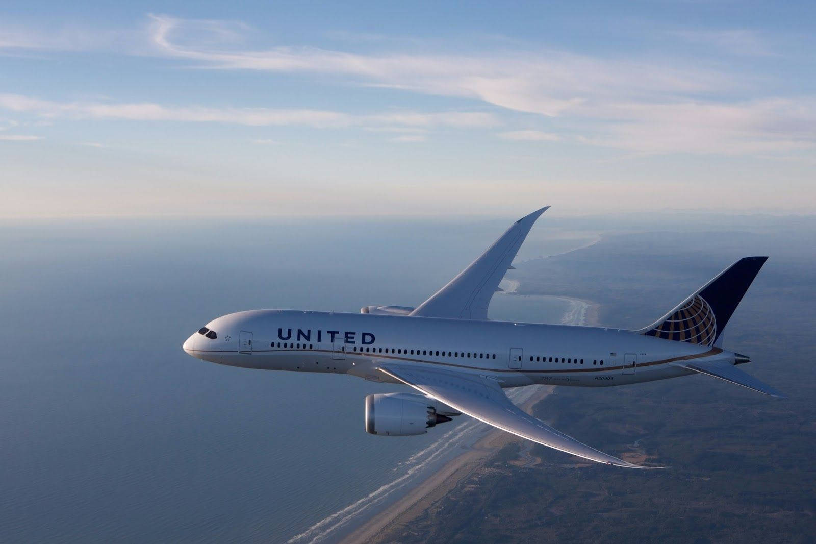 Stigende hvidt United Airplane flyver over ensfarvet blå himmel Wallpaper