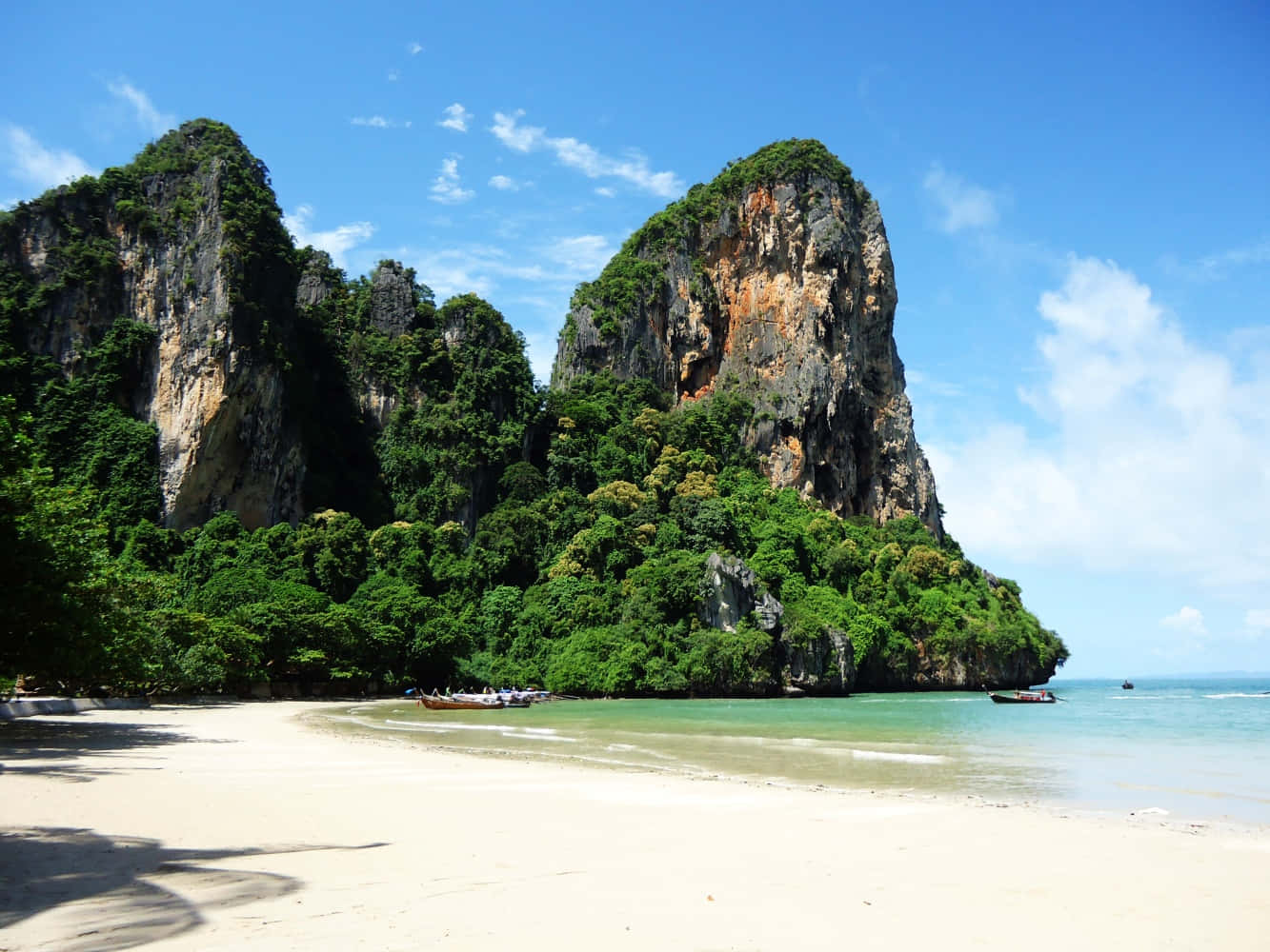 A Beach With A Large Rock Formation In The Background