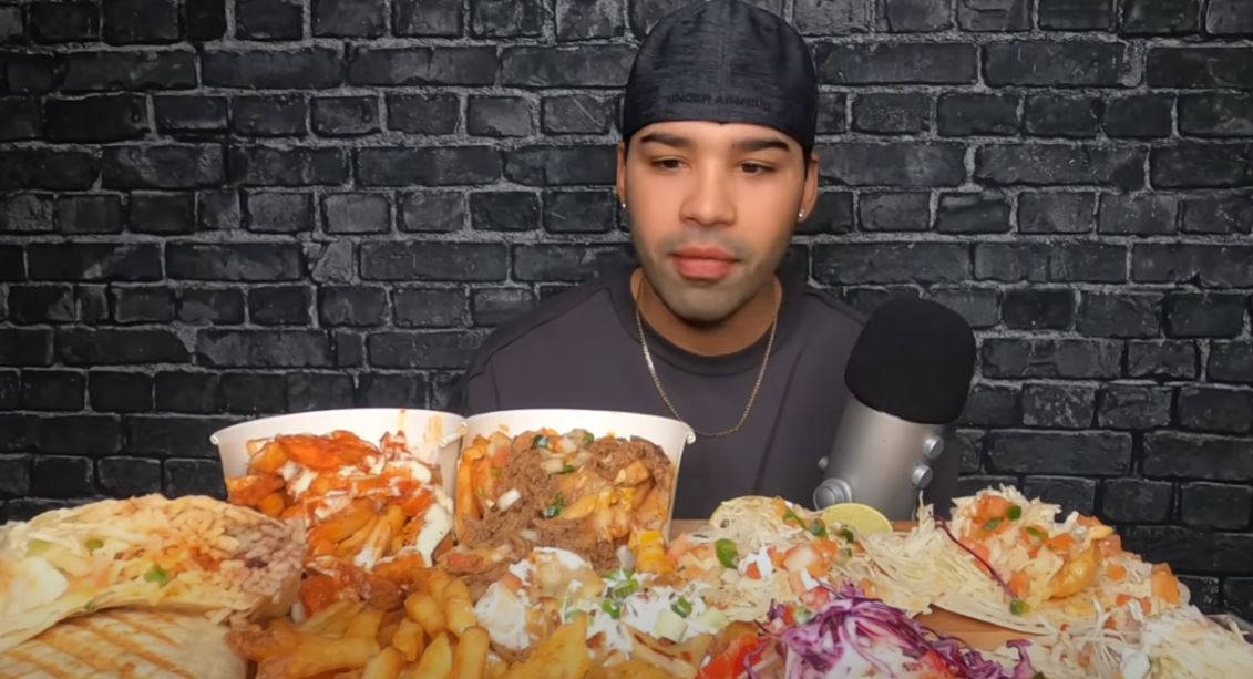 En mand med en mikrofon foran et stort fad med mad. Wallpaper