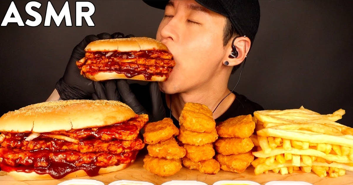 En mand spiser en stor burger med pomfritter. Wallpaper