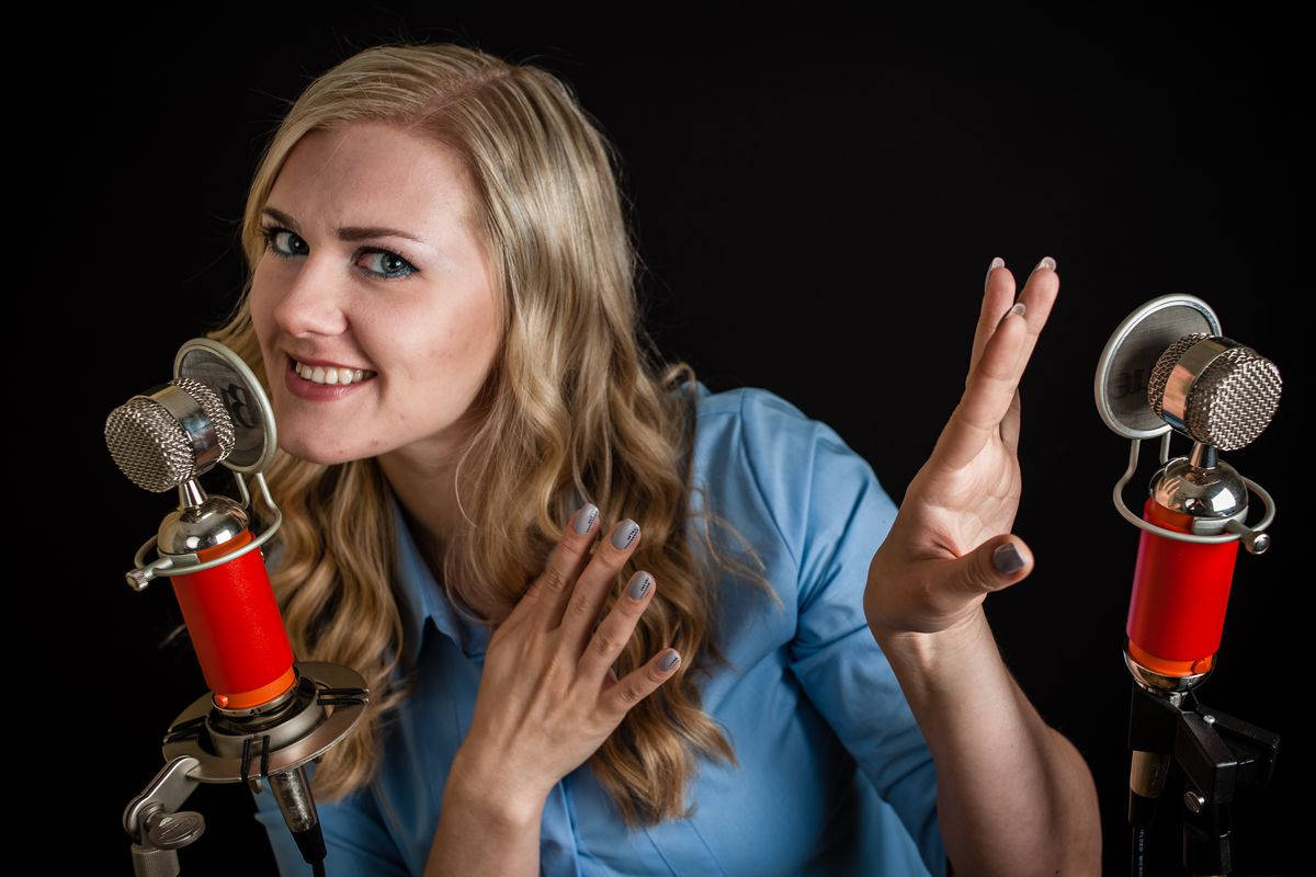 En kvinde holder et mikrofon og gør en gestus med sin hånd Wallpaper