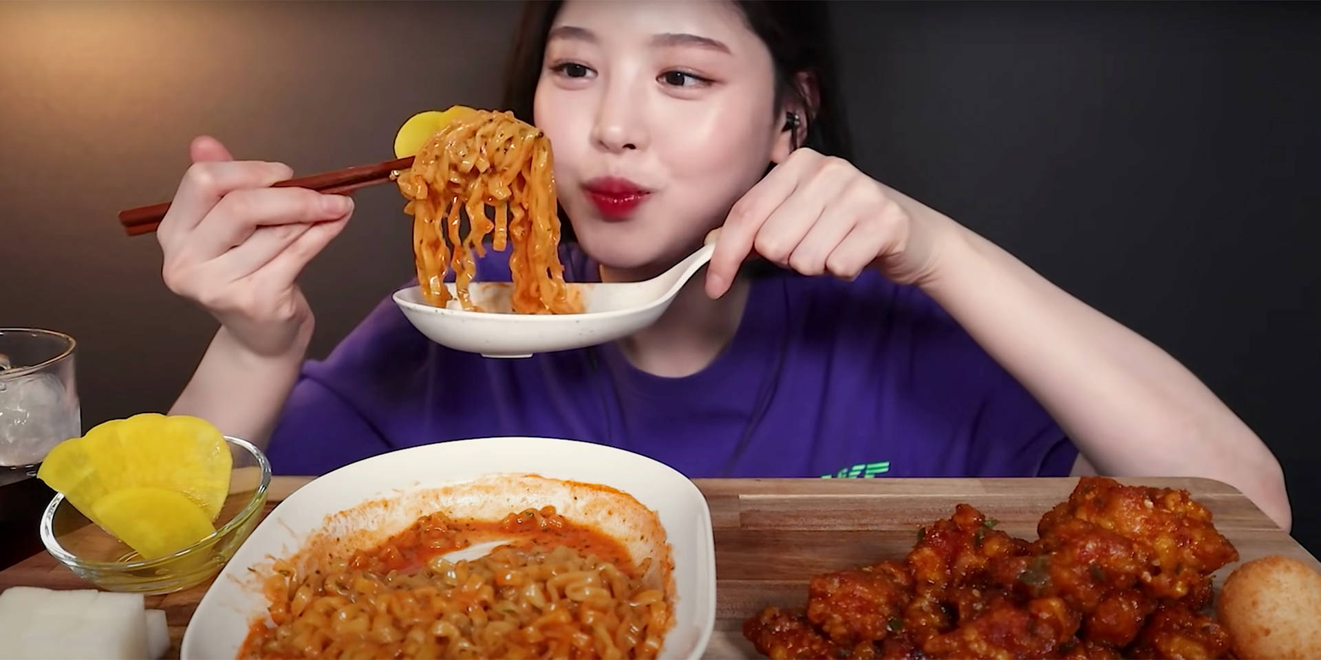 A Woman Eating Noodles With A Spoon Wallpaper