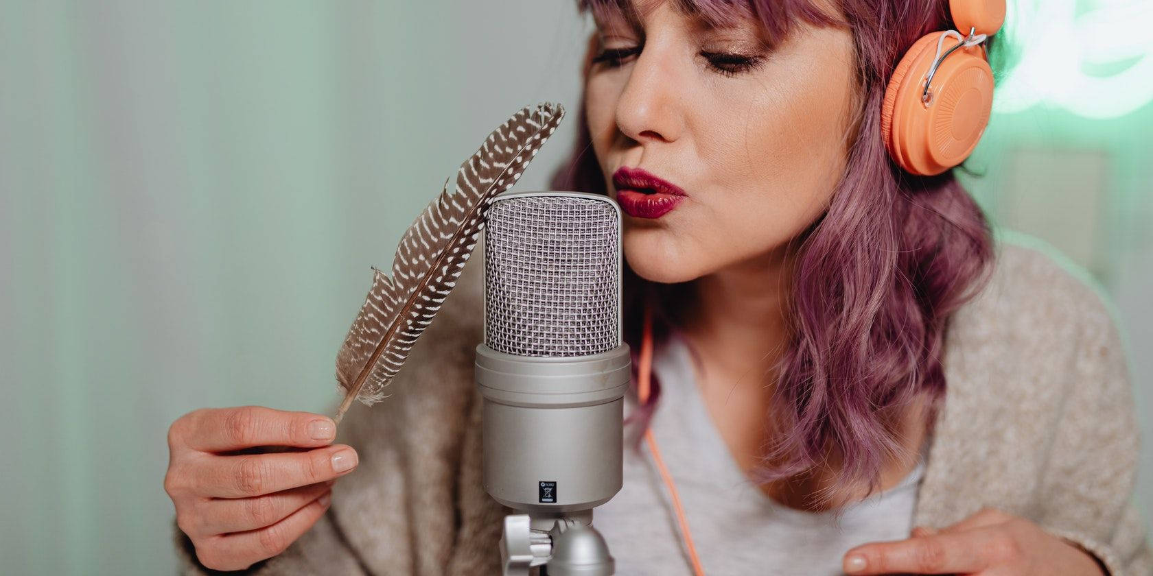 Einefrau Mit Kopfhörern Singt In Ein Mikrofon Hinein. Wallpaper