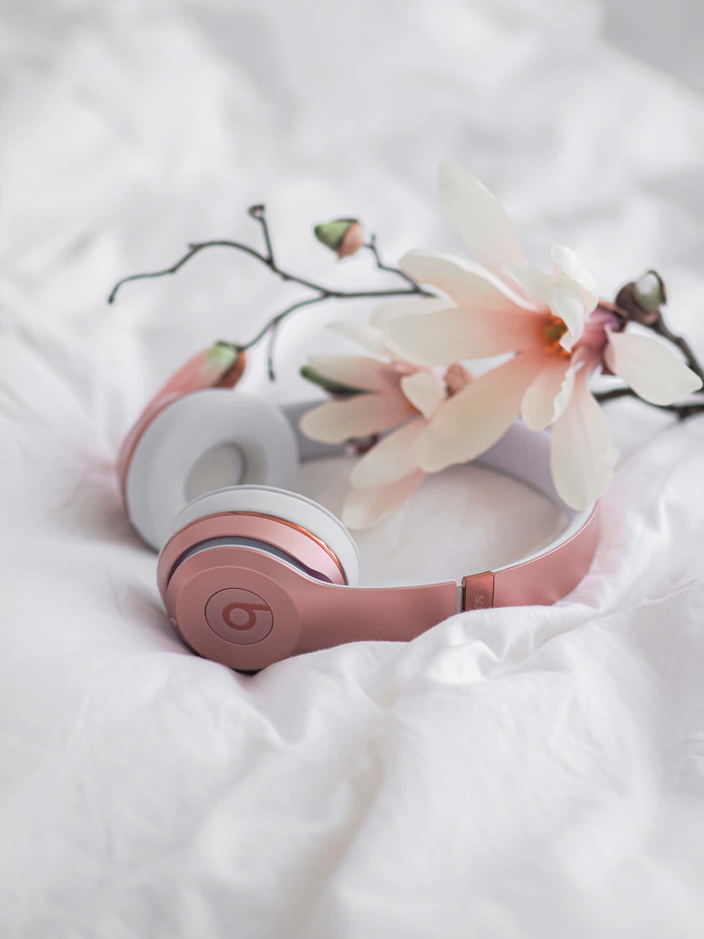 Pink hovedtelefoner på en hvid seng med blomster Wallpaper
