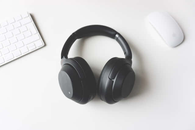 A Pair Of Headphones On A Desk Next To A Keyboard Wallpaper