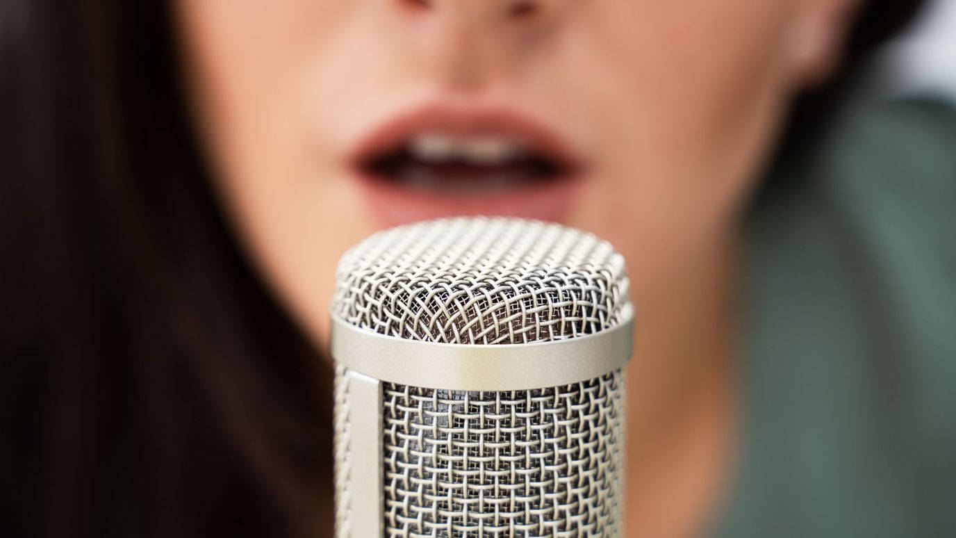 Einefrau Singt In Ein Mikrofon. Wallpaper