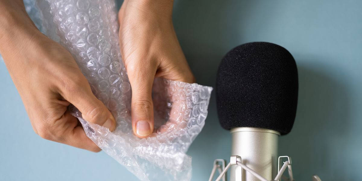 En person holder et mikrofon og pakker et stykke bobleplast ind. Wallpaper