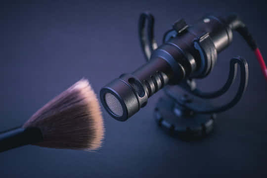 A Makeup Brush Is Placed On A Microphone Wallpaper