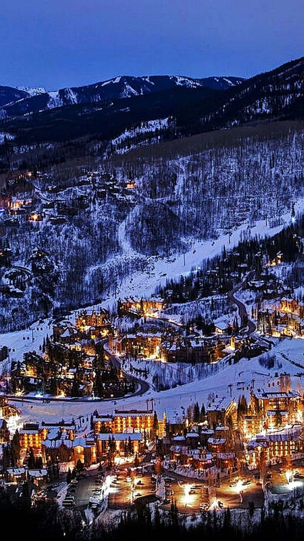 A Town Is Lit Up At Night With Snow On The Ground