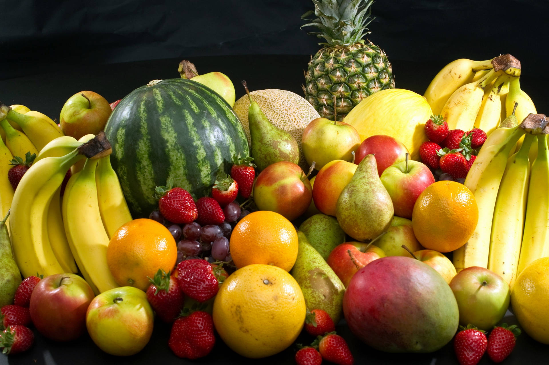 A delicious assortment of exotic tropical fruits, including a ripe yellow pineapple. Wallpaper