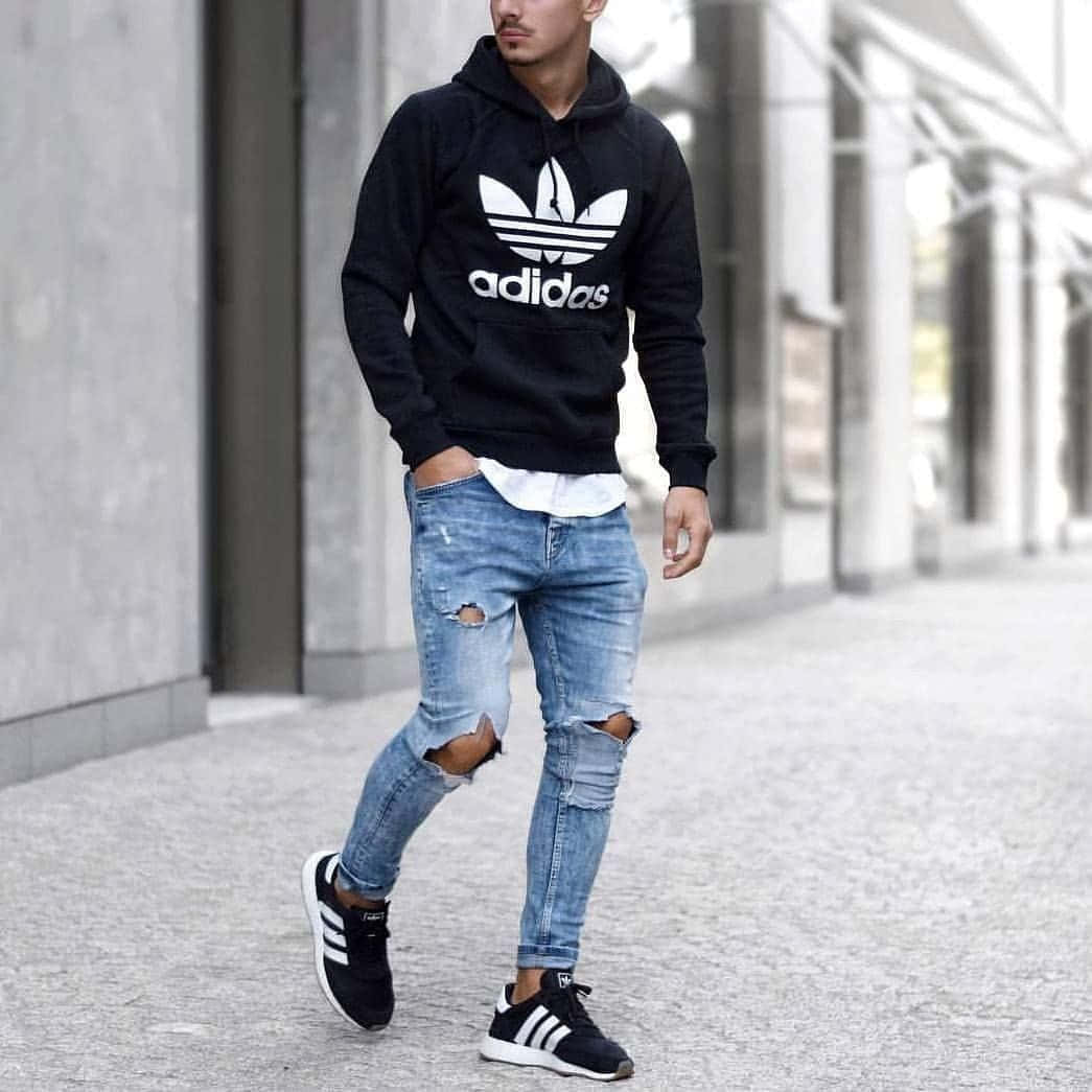 A Man In Ripped Jeans And Adidas Sneakers