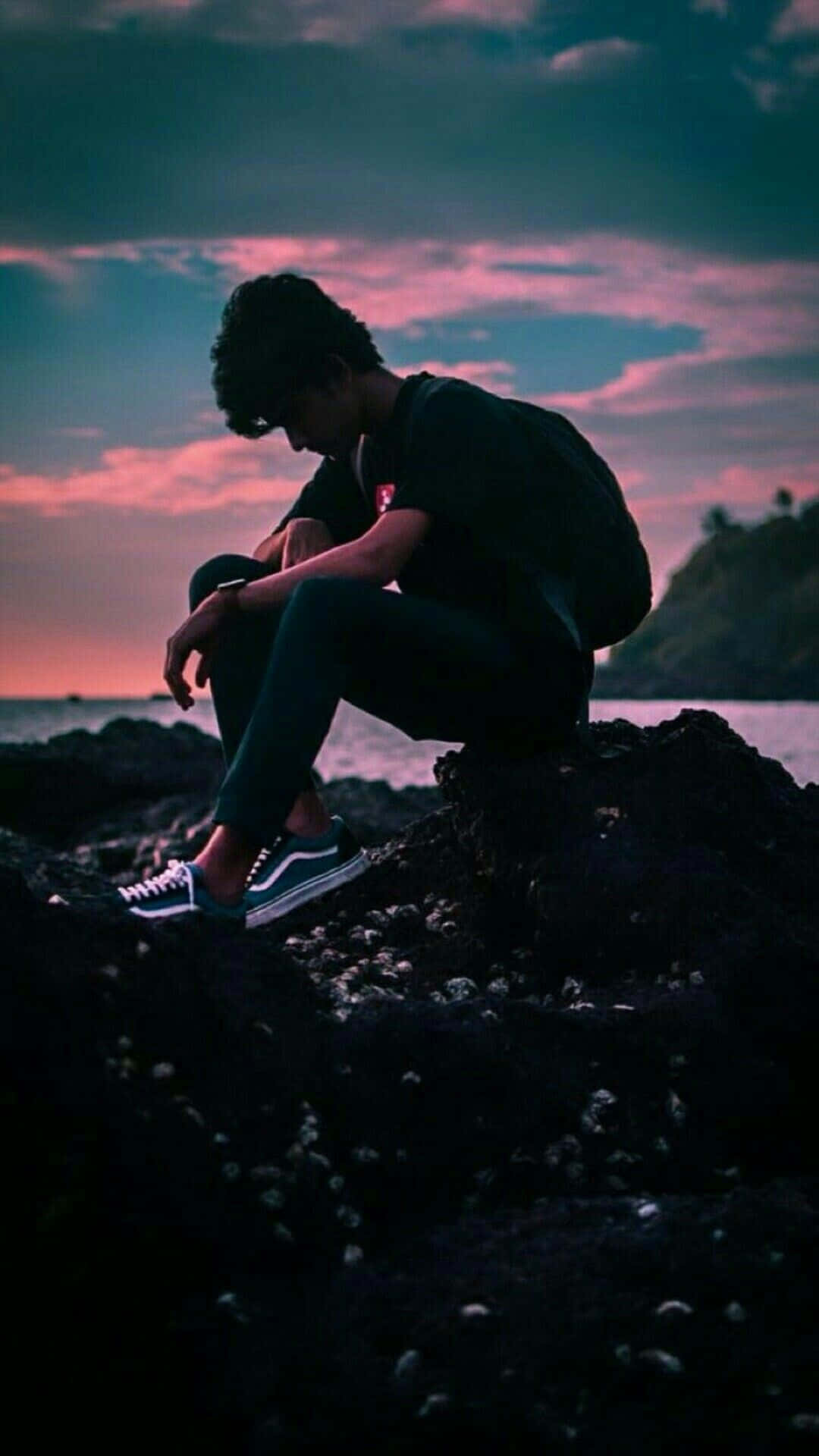 A Man Sitting On Rocks