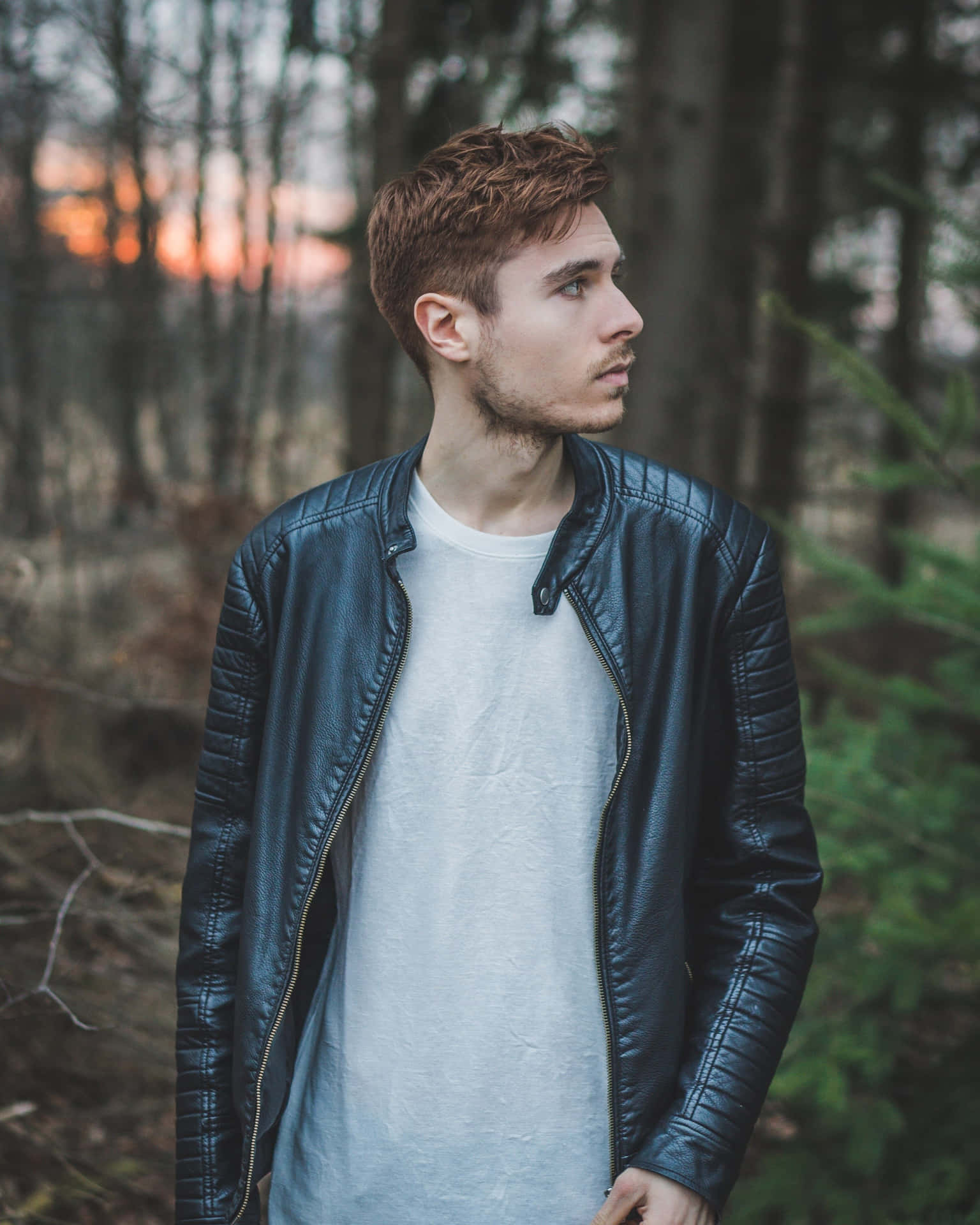 A Man In A Leather Jacket Standing In The Woods