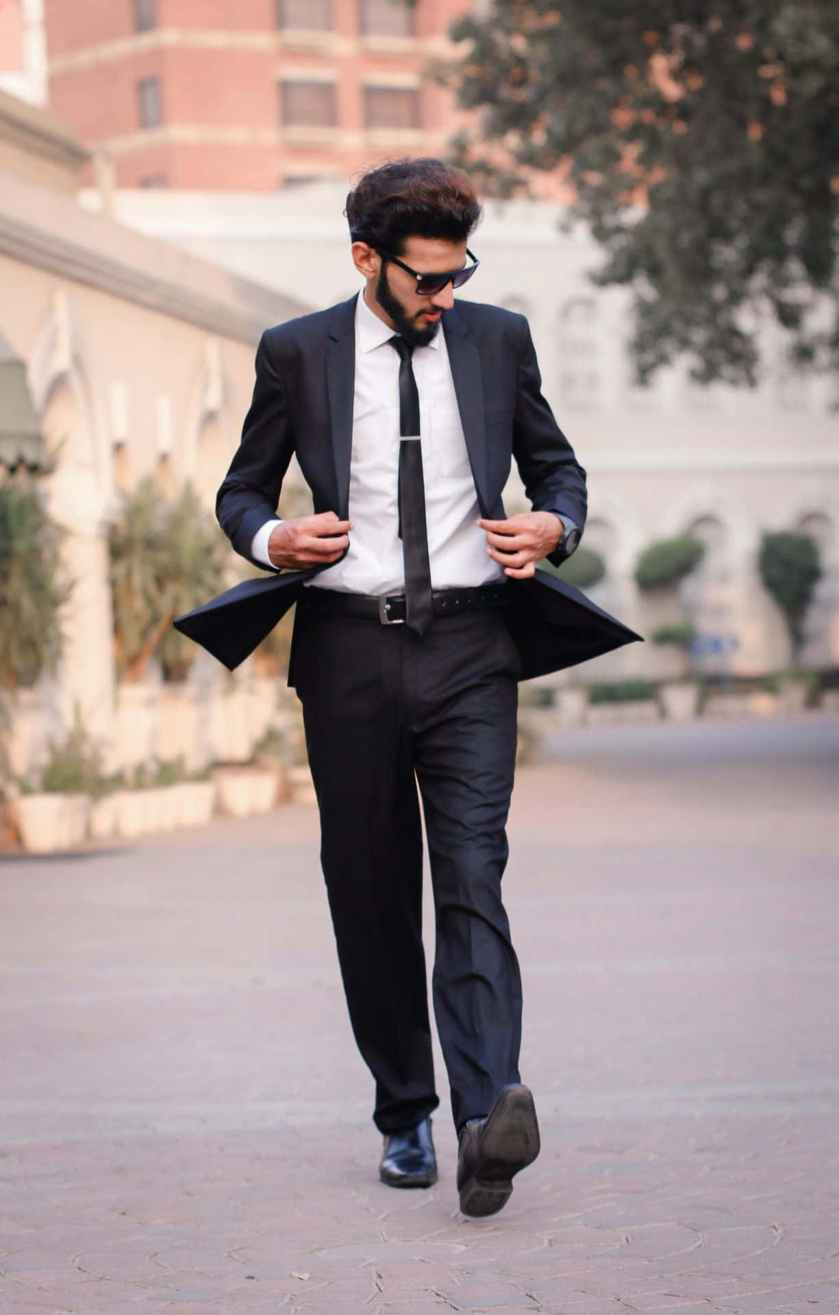 A Man In A Suit Walking Down A Street