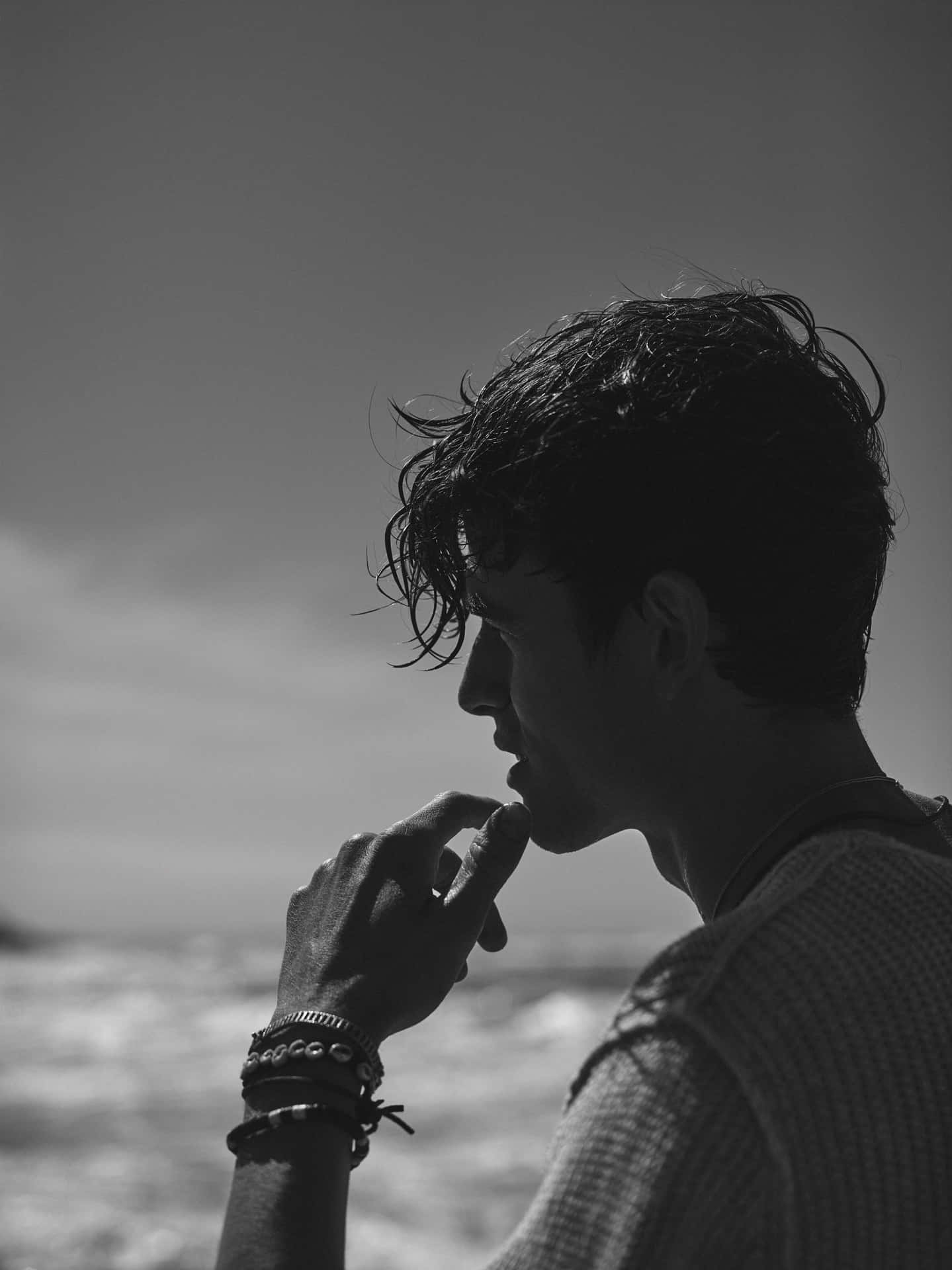A Man Is Looking At The Ocean While Smoking A Cigarette