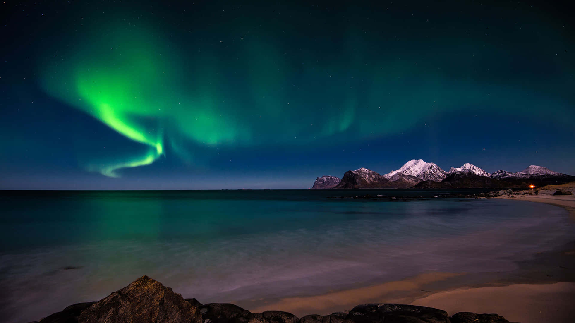 The Aurora Borealis Over A Beach And Mountains