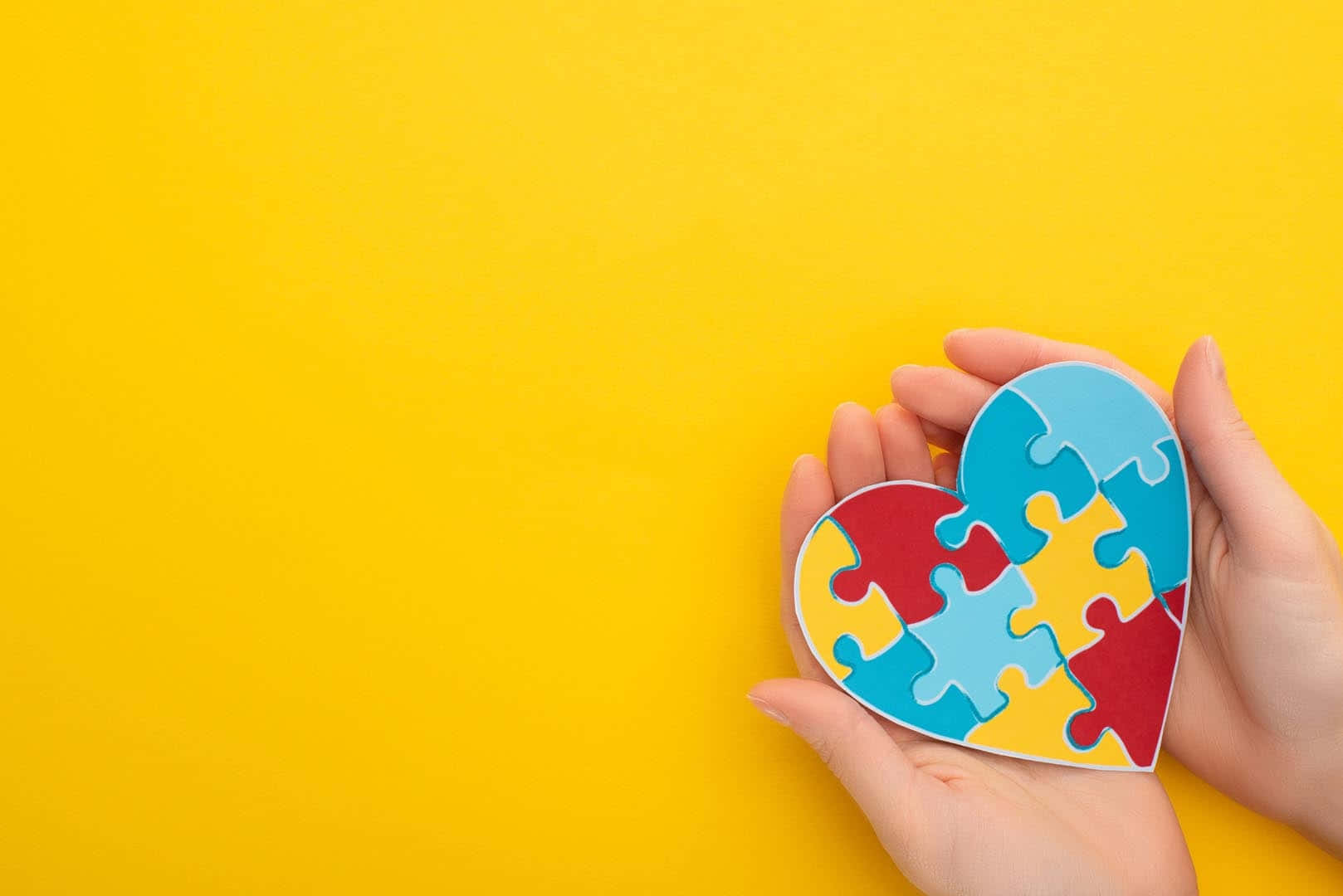 A Person's Hands Holding A Heart Shaped Puzzle Piece