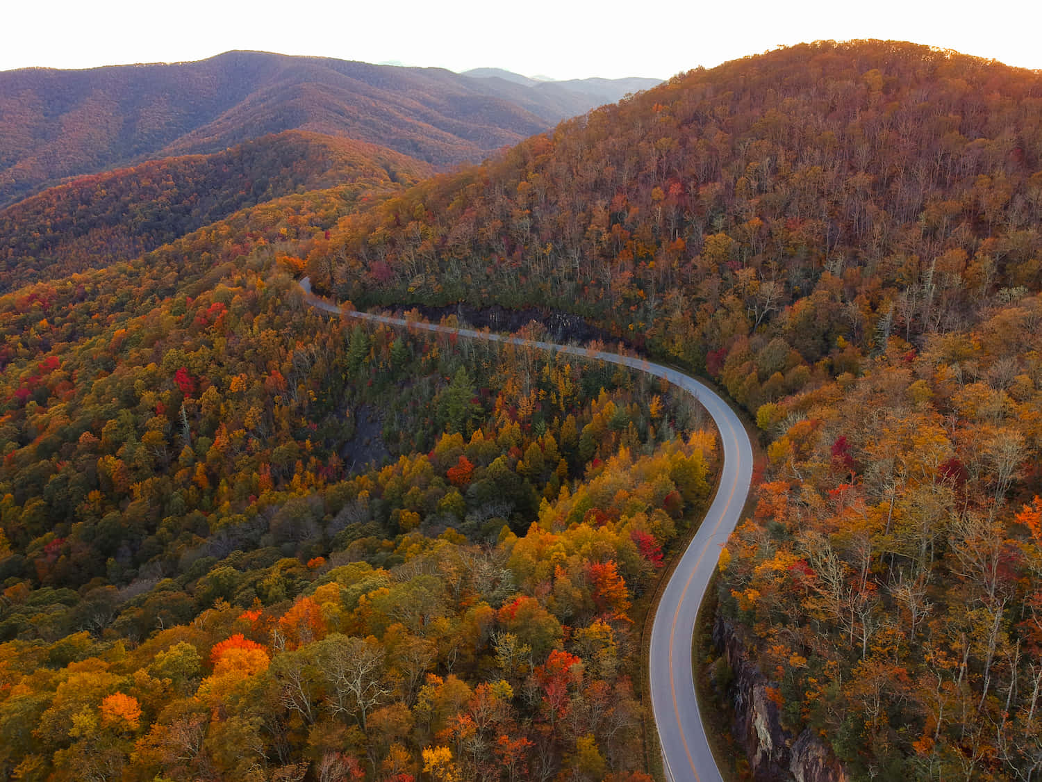 A Winding Road In The Mountains With Autumn Colors