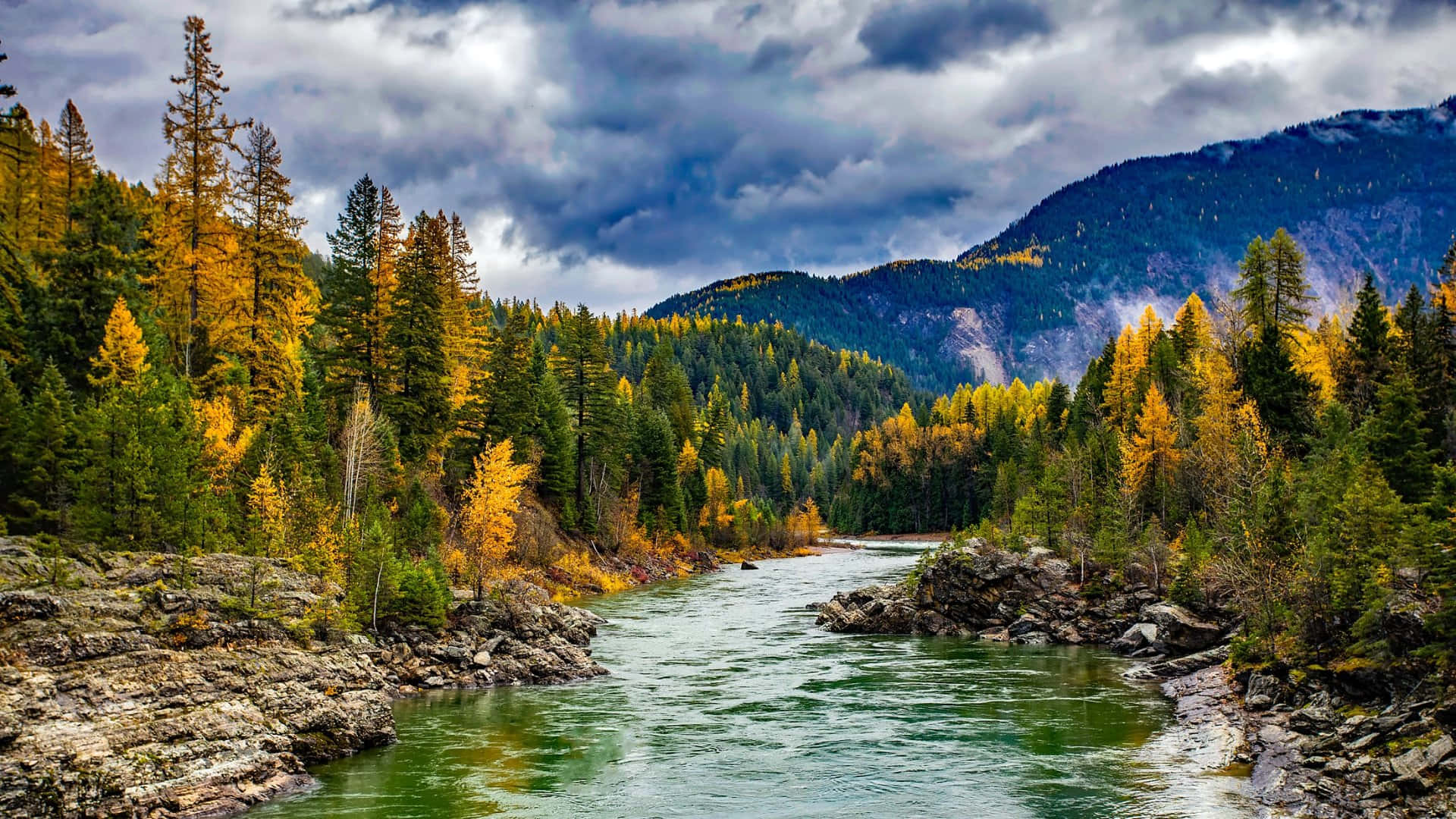 Autumn_ River_ Flanked_by_ Forested_ Mountains.jpg Wallpaper