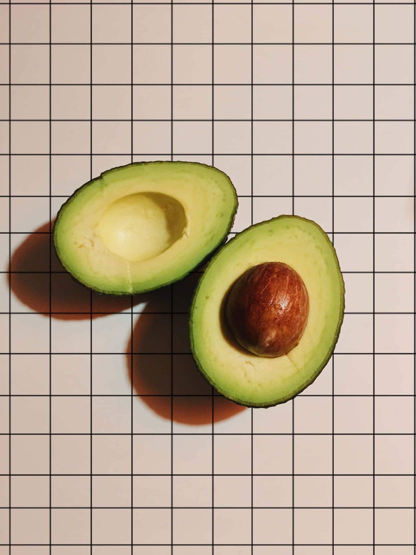 Two Avocados On A Grid Background