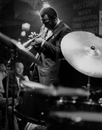 Vinprisvindende trompetist Miles Davis stride over et røgfyldt jazzrum. Wallpaper
