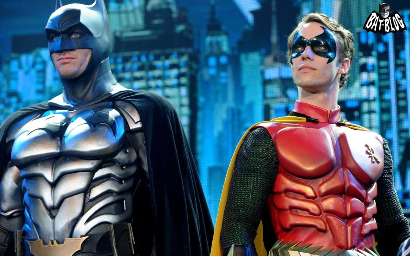 Two Batman And Robin Costumes Standing Next To Each Other Wallpaper