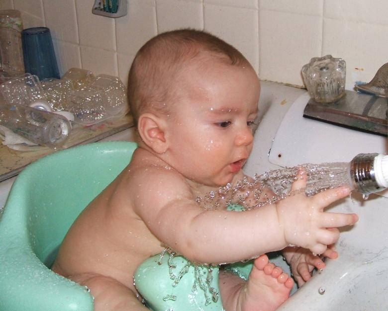 Et lille dreng der leger med vand i badekaret. Wallpaper