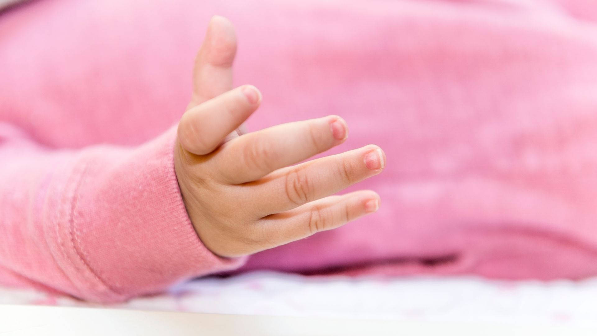 An Adorable Baby Hand in a Pink Onesie Wallpaper