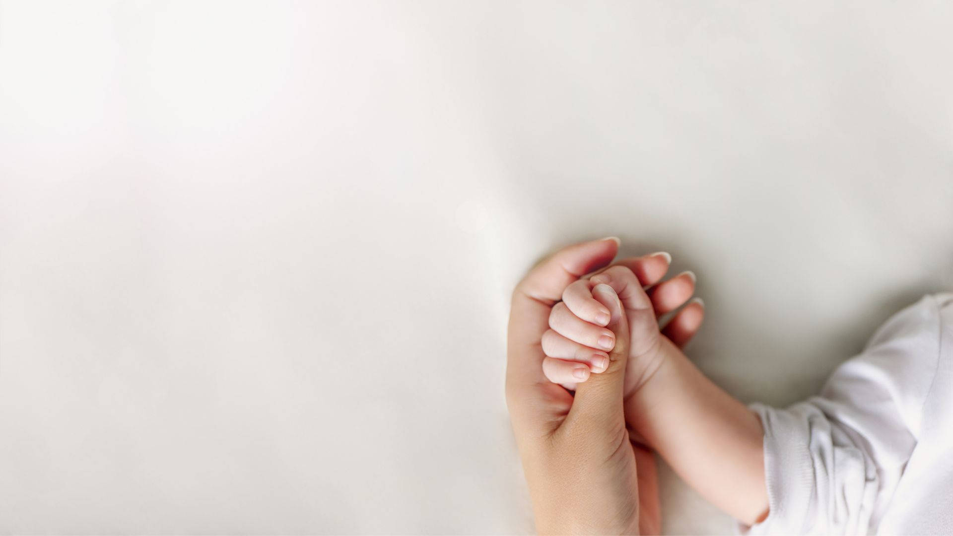 Babyhånd der ligger med moderhånden Wallpaper