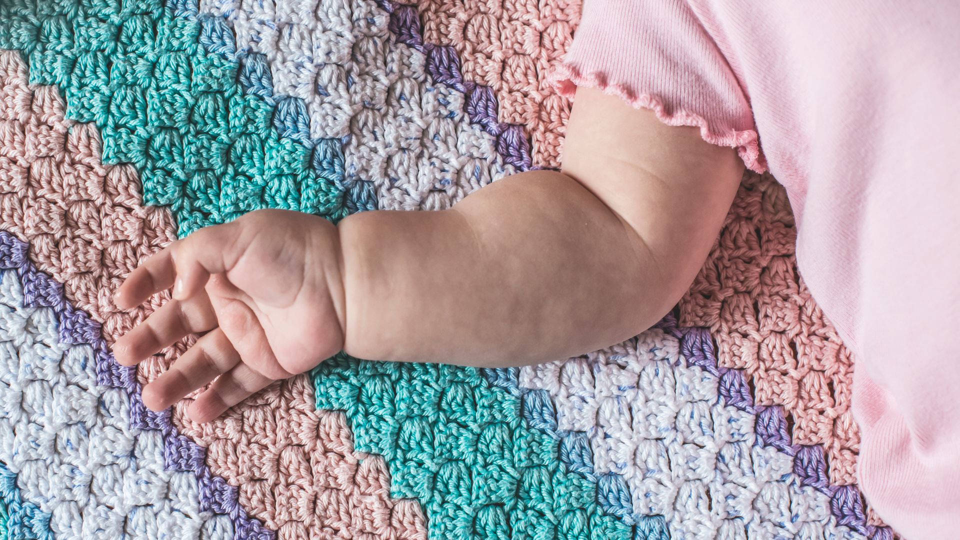 Baby Hand On A Colorful Fabric Wallpaper