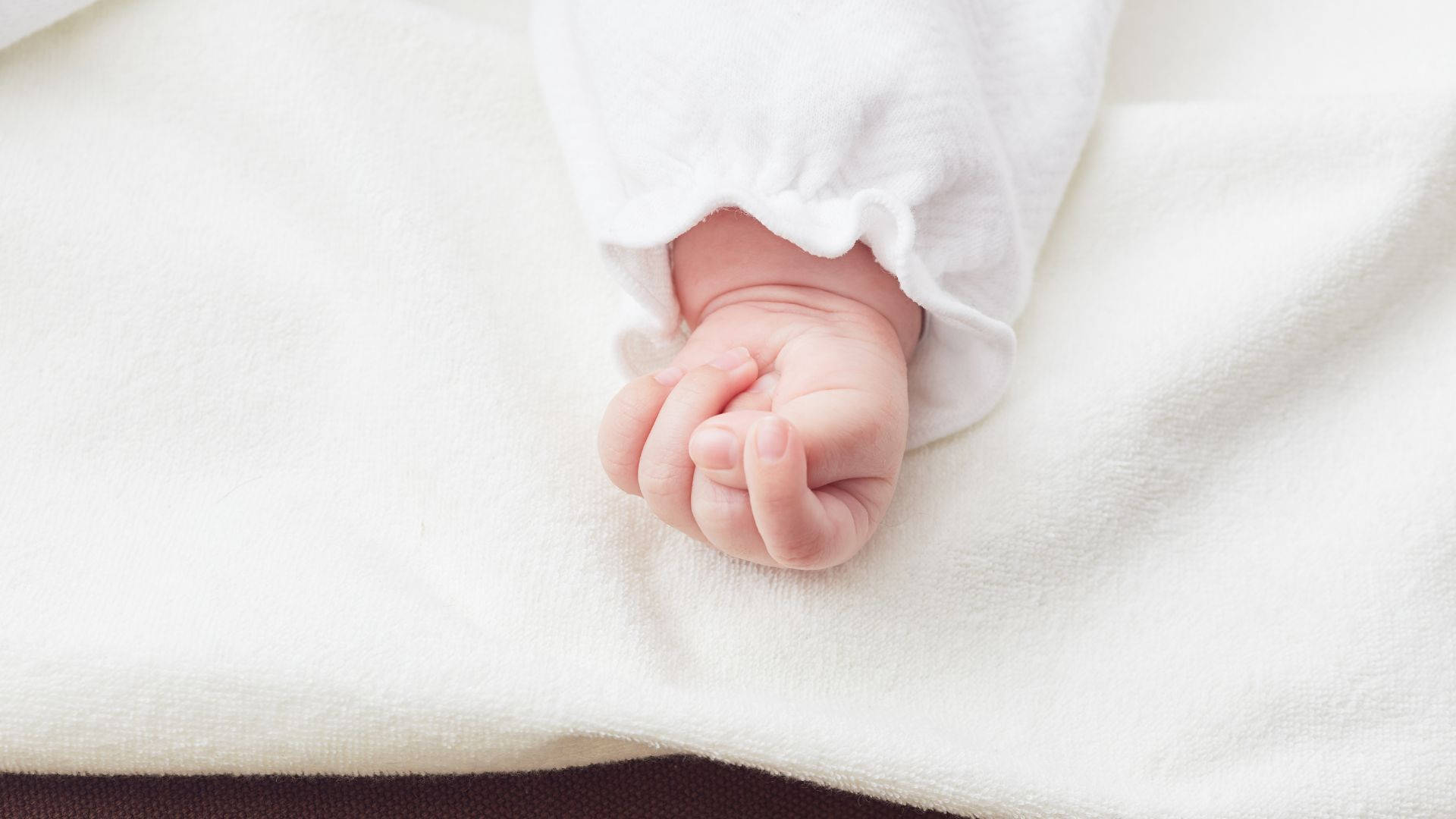 Babyhånd bærer et hvidt outfit Wallpaper